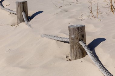 Kum tepelerinde deniz kenarında işaretlenmiş bir ip.