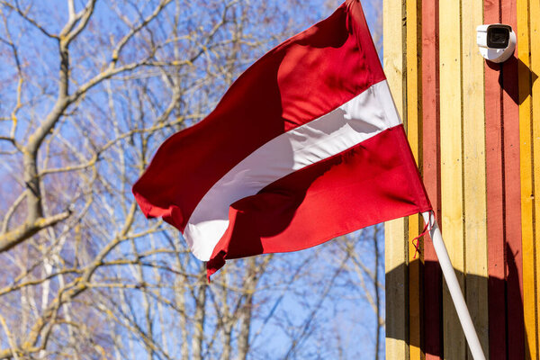Latvian flag on a colorful wall, among trees and light