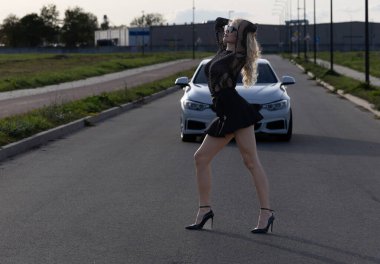 Lüks bir aracın yanında poz veren zarif sarışın güzel kadın..