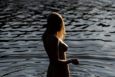 Altın saat boyunca sakin suda duran zarif bir kadın. Işık ve gölgenin oyunu kıvrımları ve yansımaları ortaya çıkarır, zarafeti, gücü ve huzuru yakalar. Su, ışık ve insan formu arasında şiirsel bir an.