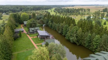 Sventoji, Palanga, Litvanya yakınlarındaki Zelv Village SPA 'nın hava manzarası. Ahşap kulübeler, göl ve modern spa tesisleri ve spor alanları olan orman çevreleri. 07 29 2025