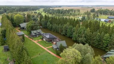 Sventoji, Palanga, Litvanya yakınlarındaki Zelv Village SPA 'nın hava manzarası. Ahşap kulübeler, göl ve modern spa tesisleri ve spor alanları olan orman çevreleri. 07 29 2025