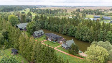 Sventoji, Palanga, Litvanya yakınlarındaki Zelv Village SPA 'nın hava manzarası. Ahşap kulübeler, göl ve modern spa tesisleri ve spor alanları olan orman çevreleri. 07 29 2025