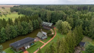 Sventoji, Palanga, Litvanya yakınlarındaki Zelv Village SPA 'nın hava manzarası. Ahşap kulübeler, göl ve modern spa tesisleri ve spor alanları olan orman çevreleri. 07 29 2025