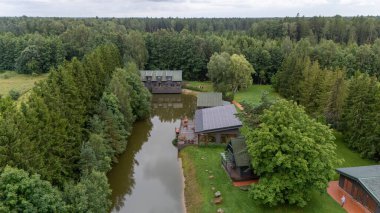 Sventoji, Palanga, Litvanya yakınlarındaki Zelv Village SPA 'nın hava manzarası. Ahşap kulübeler, göl ve modern spa tesisleri ve spor alanları olan orman çevreleri. 07 29 2025