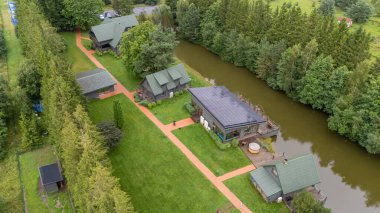 Sventoji, Palanga, Litvanya yakınlarındaki Zelv Village SPA 'nın hava manzarası. Ahşap kulübeler, göl ve modern spa tesisleri ve spor alanları olan orman çevreleri. 07 29 2025