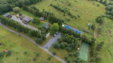 Sventoji, Palanga, Litvanya yakınlarındaki Zelv Village SPA 'nın hava manzarası. Ahşap kulübeler, göl ve modern spa tesisleri ve spor alanları olan orman çevreleri. 07 29 2025