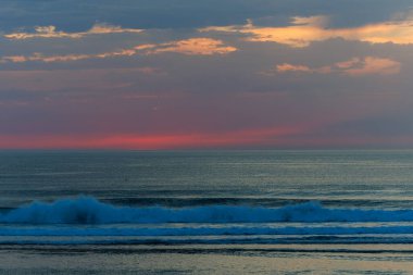 Ufukta parlak kırmızı ve turuncu tonlarla okyanusun üzerinde canlı bir günbatımı. Sakin deniz dalgaları huzurlu ve dramatik bir deniz manzarası yaratır. Doğa, seyahat ve rahatlama kavramları için mükemmeldir..