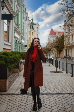 Cüzdanı olan bir kadın sokakta cep telefonuyla konuşuyor..