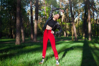 Formda genç bir kadın, bereketli, güneşli bir orman ortamında, sağlıklı ve zinde bir şekilde geriliyor.