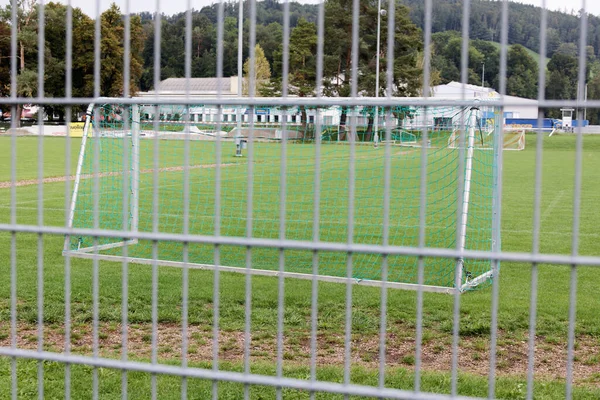 Yeşil çayırda bir bariyerin arkasında futbol golü. Yazı işleri. İnsansız hava bulutlu