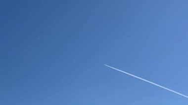Mavi gökyüzünde uzun bir uçak yolu. Uçak mavi gökyüzünde uçuyor ve bir yoğunlaşma izi bırakıyor. Stok videosu. 4K