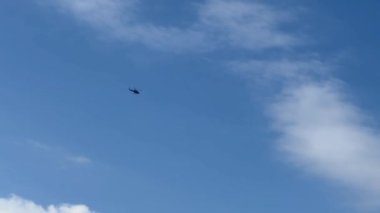Beyaz bulut ve mavi gökyüzünün arka planında bir helikopter uçuyor. Stok videosu. 4K