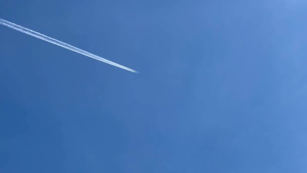 青い空に飛行機の長いトレイル 飛行機は青空に飛び 結露の跡を残します ストックビデオだ — ストック動画