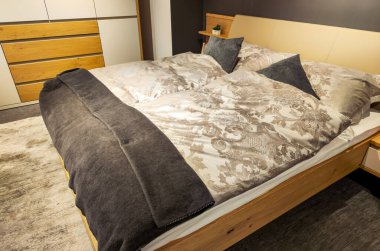 Yastıklı ve battaniyeli rahat ve davetkar bir çift kişilik yatak güzel ışıklandırmalı bir uyku odasında.
