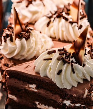 Lezzetli ve çok lezzetli çikolatalı pasta, büyük beyaz krema çiçekleri ve çikolata parçaları.