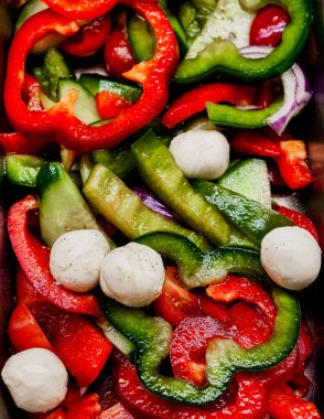 Kırmızı ve yeşil dolmalık biberli taze sebze salatası, kiraz domatesleri, salatalık, kırmızı soğan ve mozzarella topları. Sağlıklı yiyecekler, organik malzemeler, diyet yemeği, Akdeniz mutfağı..