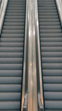 Modern alışveriş merkezinde ya da metro istasyonunda yürüyen merdivenlerin yavaş çekim videosu. Kentsel arkaplan veya mimari görüntüler için simetrik kompozisyon ve minimal tasarım.