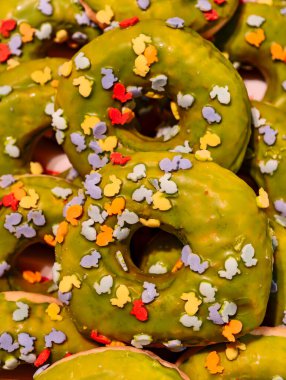 Renkli tavşan şekilli donutlarla süslenmiş yeşil donutlar neşeli Paskalya pastaları, canlı şekerlerin yakın çekimi, bahar için mükemmel, tatil ikramı, pastane ve tatlı teması.