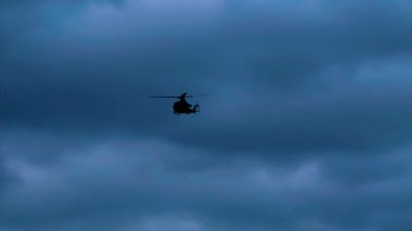 Bulutlu Mavi Gökyüzüne Karşı Askeri Helikopterin Silueti dramatik ve güçlü bir sahne yaratıyor, Havacılık ve Askeri Temalar İçin Mükemmel