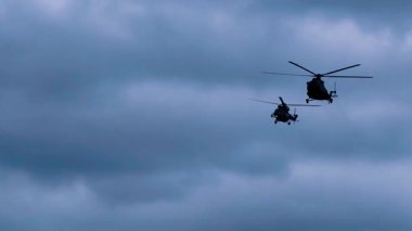 Mavi gökyüzünde uçan iki askeri helikopterin siluetleri, havacılık geçmişi, ordu hava harekatı, savaş hava devriyesi, taktik helikopter manevrası.