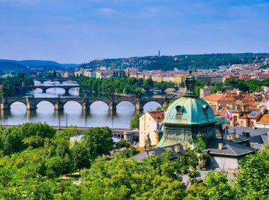 Prag 'ın çarpıcı panoramik manzarası, ikonik Charles Köprüsü' nü ve nehir kıyıları boyunca yemyeşil alanları gösteriyor. Canlı şehir manzarası, tarihi mimarinin güzel bir karışımını vurguluyor.