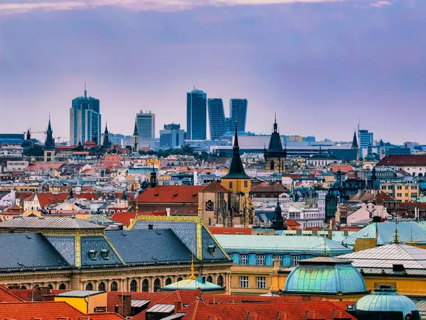Prag 'ın ufuk çizgisinin panoramik görüntüsünde tarihi çatılar ve modern gökdelenlerin yumuşak bir alacakaranlık gökyüzü altında karışımı, kentin zengin tarihi arasında büyüleyici bir zıtlık yaratıyor.