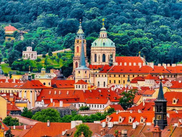 Prag 'ın tarihi çatılarının göz kamaştırıcı manzarası, yemyeşil bir zemin üzerine kurulmuş canlı bir terracotta fayansları sergileniyor. Belirgin kubbeleri ve kuleleri olan seçkin kiliseler.