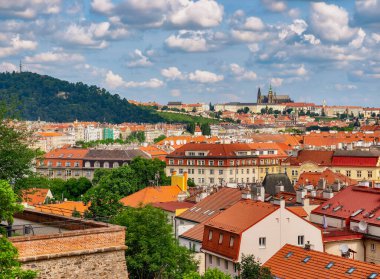 Prag 'ın Skyline' ı: Kırmızı Döşemeli Çatı ve Tarihsel Mimarinin Büyüleyici Manzarası Pofuduk Bulutlu Parlak Mavi Gökyüzü, Şehirlerin Eşsiz Büyüsünü Gösterme ve Zamansız Güzellik. Stok fotoğrafı