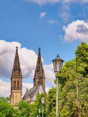 Yeşillik ve açık mavi gökyüzü ile çevrili Gotik katedralde tarihi mimarinin cazibesini artıran klasik sokak lambaları var..