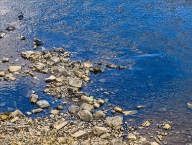 Rocky Shoreline ile Sakin Mavi Su Yüzeyi Soyutlayıcı Özgeçmiş Duvar Kağıdı, Sosyal Medya ve Dijital Tanıtımlar İçin Mükemmel