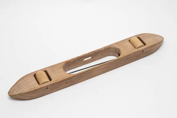 Beyaz arka planda geleneksel ahşap dokuma mekiği.