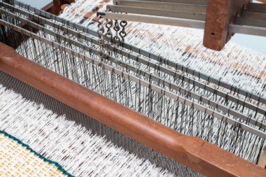 Güzelce hazırlanmış dokuma tezgahı. Tekstil işçiliğinde ve dokumada kullanılan karmaşık yapıyı vurguluyor.,