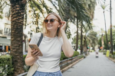 Gülümse, genç bayan. Sokakta yürürken akıllı telefonunu izliyor. Milenyum kızı açık havada mobil uygulama kullanıyor. - Evet. Yüksek kalite fotoğraf