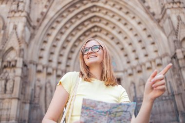 Genç iyimser kadın turist gözlüklü ve şık elbiseli mutlu gezgin Barselona, İspanya 'daki eski Barri Gotik Mahallesi' nin önünde selfie çekiyor.