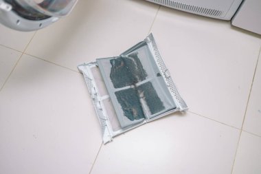 Ev hanımı temizleme bezleri ve çamaşır kurutma filtresinin kiri. İplikle kaplanmış çamaşır ipliği filtresi. Makineyi kullanmadan önce kurutma makinesinin kirli hava filtresini çıkarıyorum..