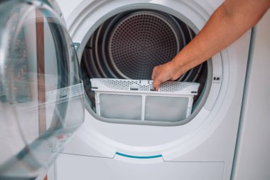 Ev hanımı temizleme bezleri ve çamaşır kurutma filtresinin kiri. İplikle kaplanmış çamaşır ipliği filtresi. Makineyi kullanmadan önce kurutma makinesinin kirli hava filtresini çıkarıyorum..