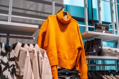 Hafif arka planda gardırop askısında sıcak süveterler. Sonbahar, kış giysileri. Alışveriş mağazası. Gdansk, Polonya, Avrupa. 