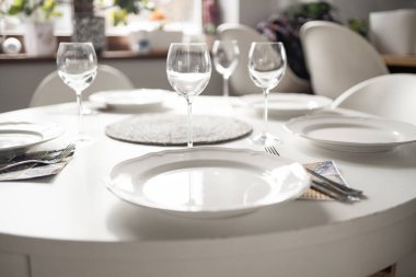 Oturma odasında boş bardaklar var. Beyaz masa örtüsü, tabaklar, kristal bardaklar. Yüksek kalite fotoğraf