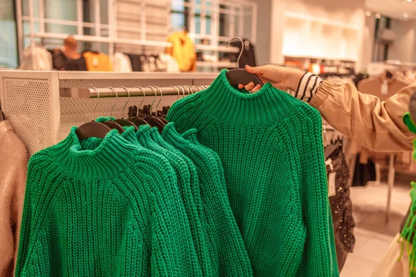 Warm sweaters on a wardrobe hanger on a light background. Autumn, winter clothes. Shopping store. Gdansk, Poland, Europe.