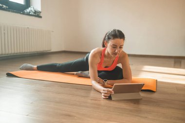 Spor kıyafetli güzel bir kadın yoga yaparken spor salonunun penceresinin önünde esneme hareketleri yapıyor.. 