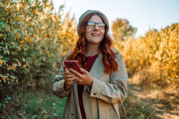 Aufgeregte Fröhliche Herbstkaukasierin Die Fröhlich Lächelt Und Das Handy Nutzt — Stockfoto