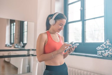 Aktif genç Kafkas spor spor spor spor antrenörü kadın akıllı telefon kullanıyor, spor salonunda müzik dinliyor. Spor sporu konsepti. 