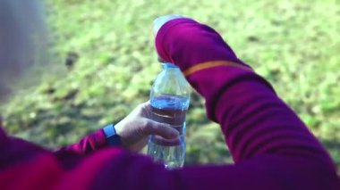 Spor kıyafetleri giyen, açık havada antrenman yapan, temiz su içen beyaz bir kadın. Sabahları su içtikten sonra dişi su dengesini sağlar. Dağlarda yürüyüş yaparken kilo verdim.