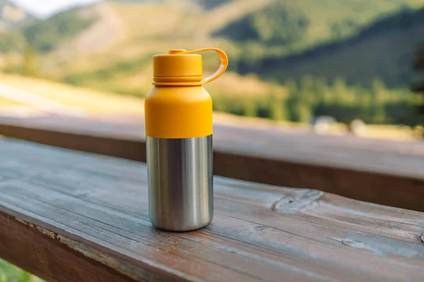 Steel vacuum thermos, outdoor. A hiking flask is in the stream.Water bottle on wooden stump in the middle of woods. Be plastic free. Zero waste. Copy space. Zero waste, no plastic.
