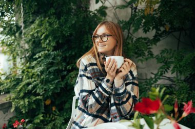 Kafkasyalı bir kız kafede çalışırken kahve içiyor ve eğleniyor. Masada oturuyor. Serbest ve uzaktan kumandalı. Modern kadın yaşam tarzı. 