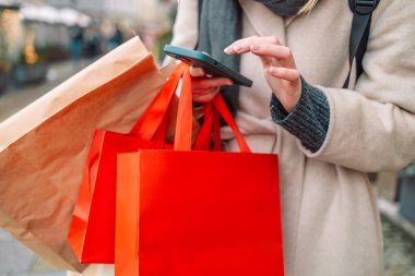 Alışveriş merkezinin yakınındaki caddede kırmızı bayram hediyelerini tutan kadınların el resimleri kullanılmış telefon paketleri. Perakende satış konsepti. Alışverişçi. Satışlar. Alışveriş Merkezi. Siber Pazartesi. Kara Cuma.