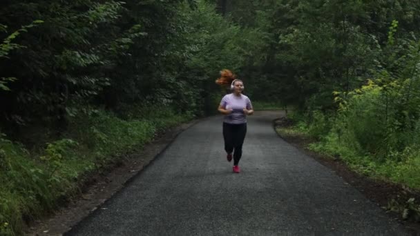 森の中を走る若い太りすぎの女性 女性のジョガーは朝の物理的なトレーニングを行う アウトドアスポーツ アクティビティ 健康的なライフスタイルと体重減少 高品質4K映像 — ストック動画