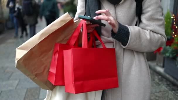 ショッピングセンターの近くの街の通りに赤い休日の贈り物パッケージを保持する女性の手の作物のイメージ 小売販売の概念 買い物客 売り上げだ ショッピングセンターサイバー月曜日黒い金曜日 — ストック動画