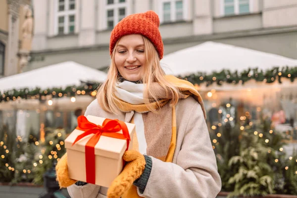 Happy young attractive woman with paper bags and gift boxes in hands after Christmas shopping in mall. Cheerful beautiful girl hold shopping bags and present boxes in hands. Winter holidays sale